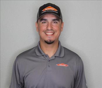 Male employee with brown hair smiling in front of a grey background.