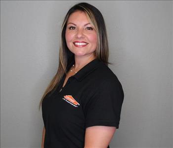 Female employee with brown hair smiling in front of a grey background.