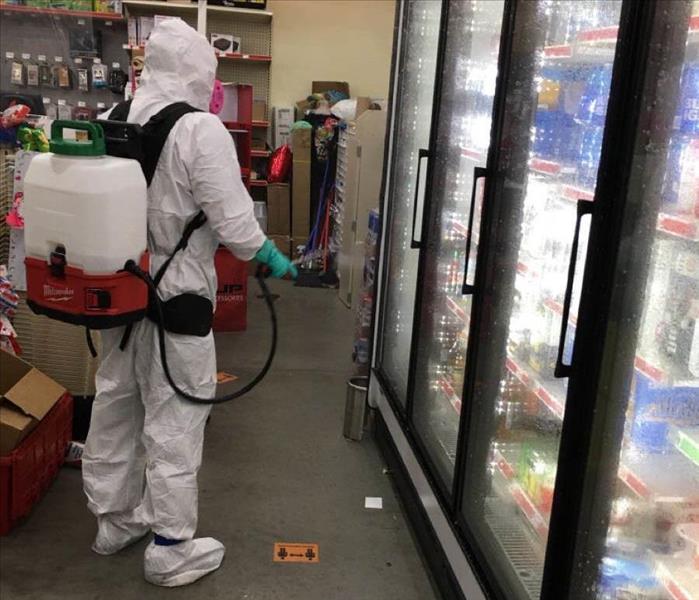 Team member in PPE cleaning a gas station.