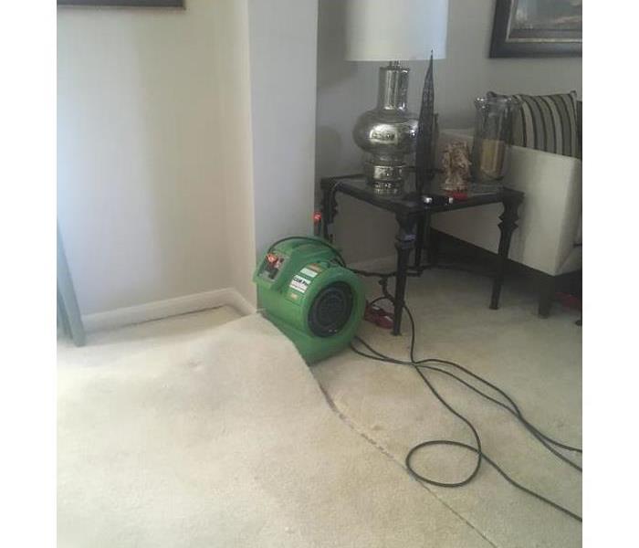 Air mover underneath carpet in water damage restoration