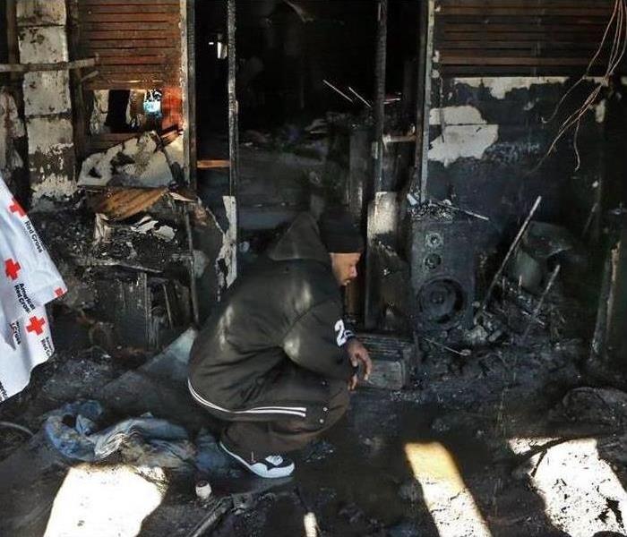 Man crouching, pensive mode around a house that burned down