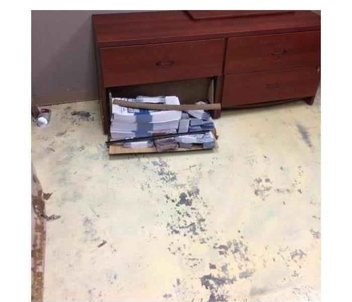 Sand and dirt on the floor, drawer one is open and has brochures inside 